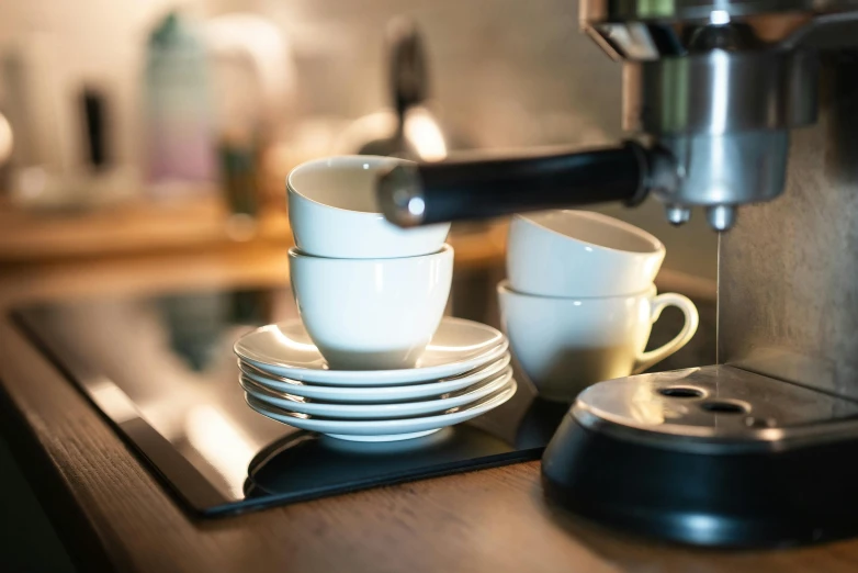 a stack of white dishes next to an espresso machine