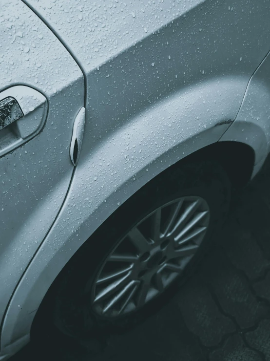 a close up of a silver car with rain drops