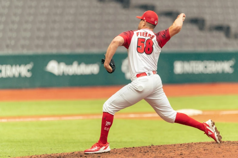 a baseball player with a red and white uniform pitching a ball