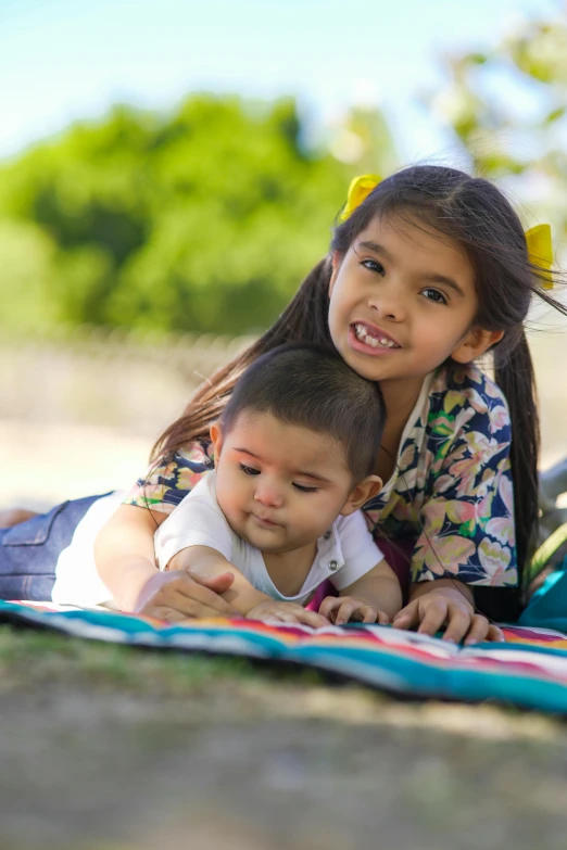 two little girls laying on a blanket