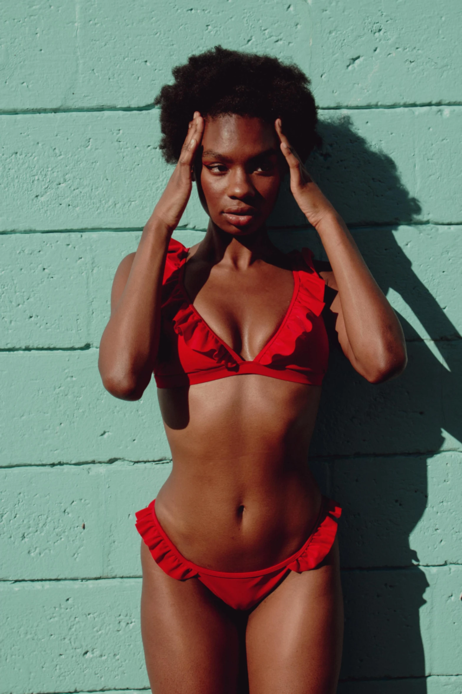 a beautiful woman in a bikini standing next to a wall