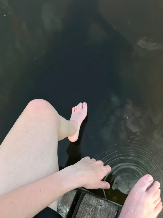 a person's legs sticking out of the water with reflection