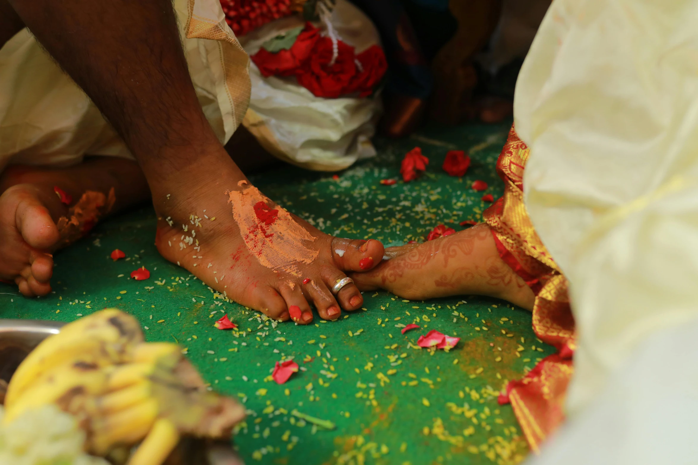 a couple standing over each other with red and gold wedding paint all around them