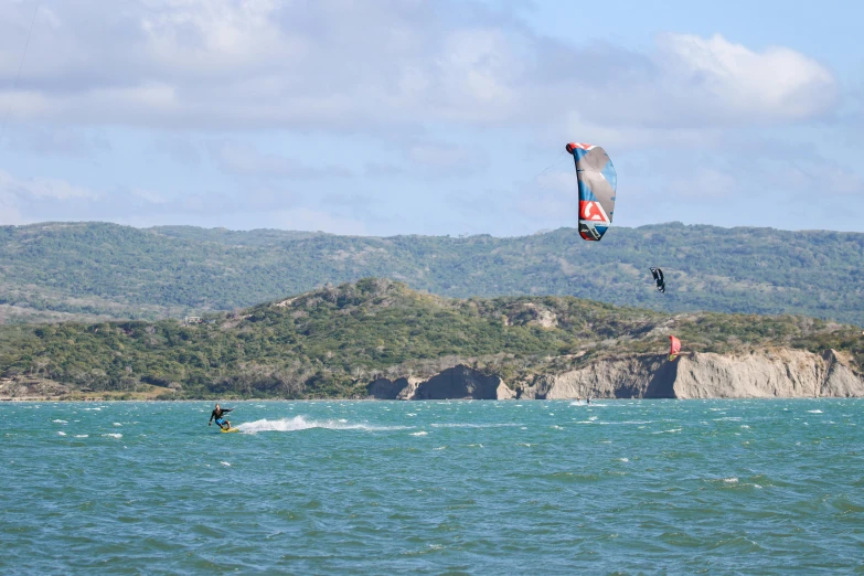 two people flying their kites in the ocean