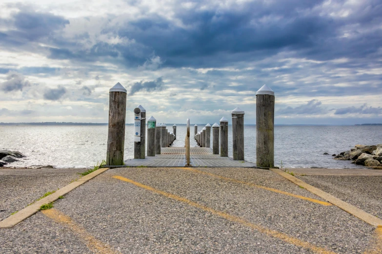 several posts with street signs on them are near the ocean