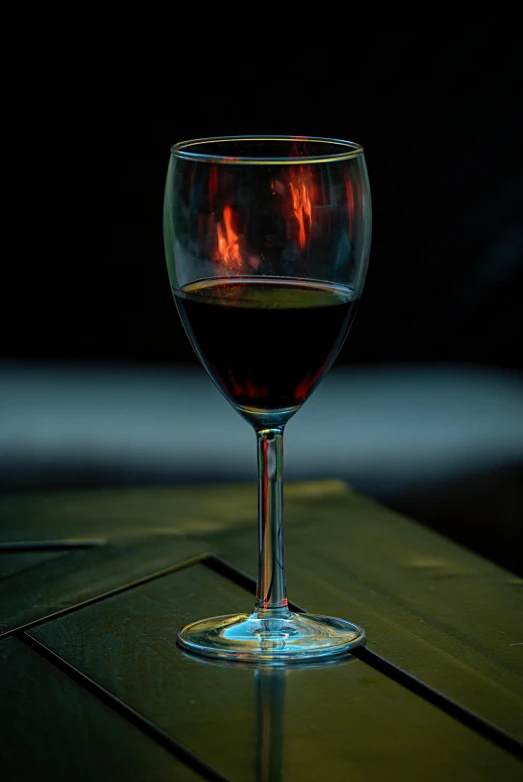 the wine glass with its reflection is illuminated by the light from the window