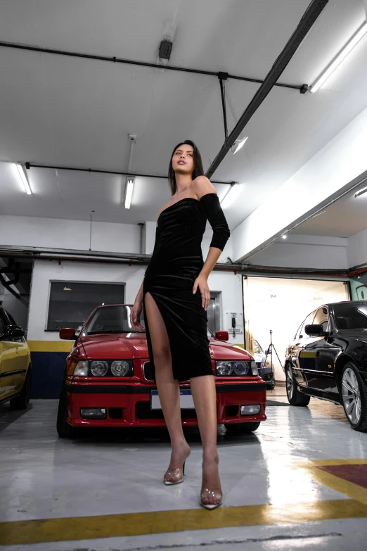 a woman in a black dress is standing near a group of cars