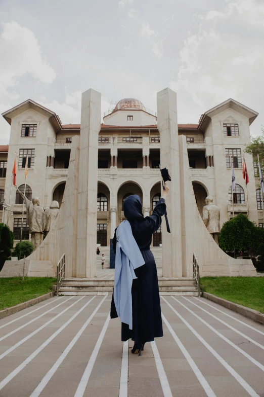 a nun holding a baby on her hip outside of a large building