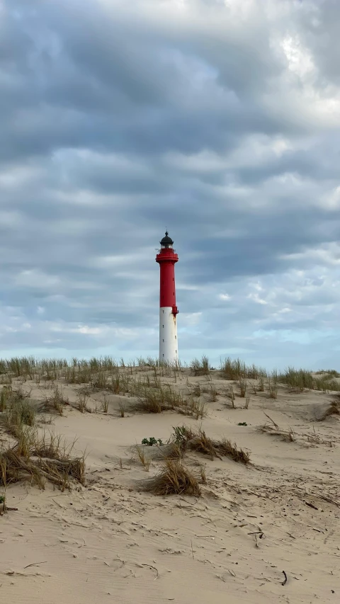 a red and white lighthouse sitting on top of sand