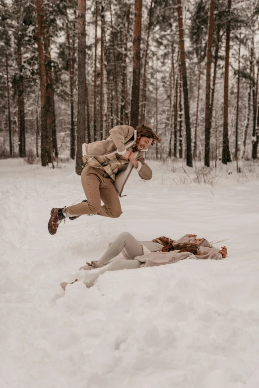 two women playing in the snow next to trees