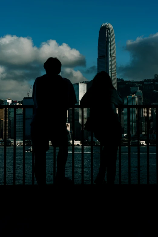 two people staring out over water, with the city in the background