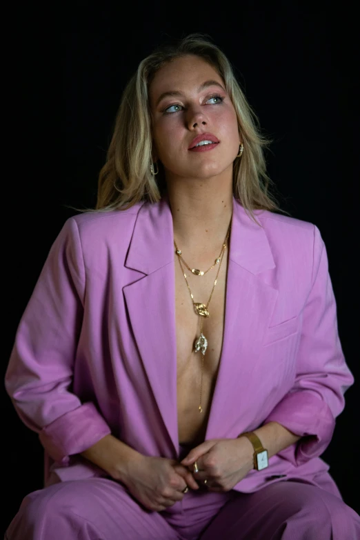 a woman in a suit and jewelry sitting on top of a chair