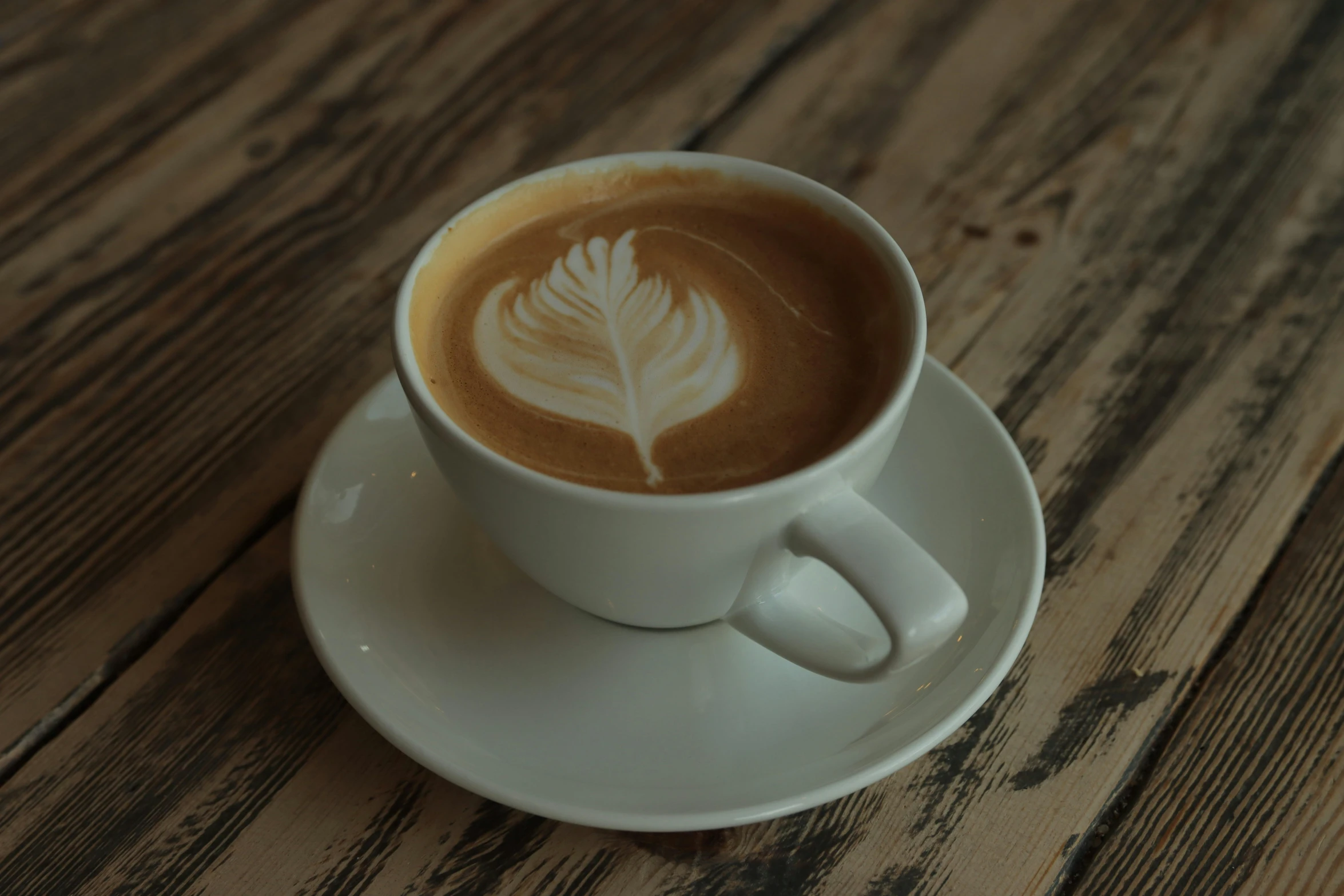 a cappuccino with a white frothy pattern on a saucer