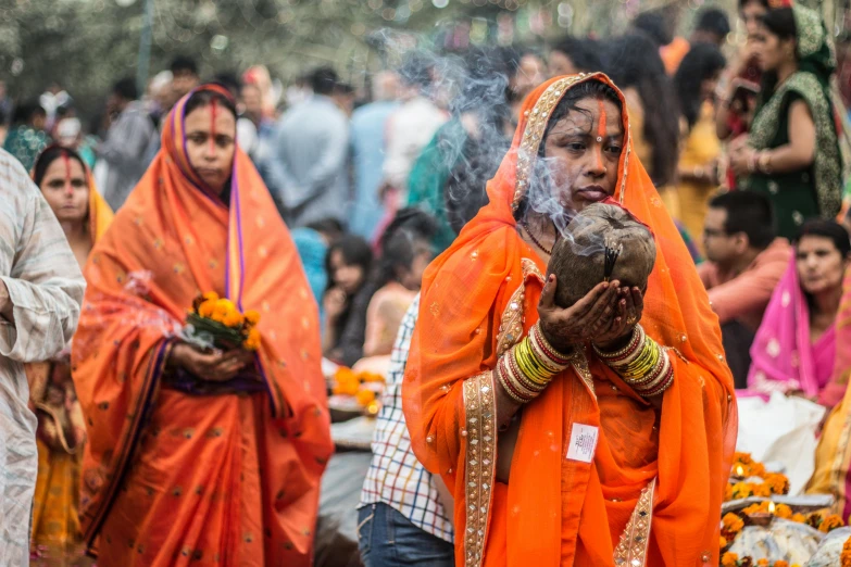a woman in orange colored clothes and her head covered in smoke