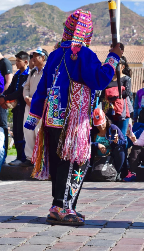 a person with a large stick dressed in colorful clothing