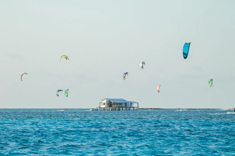 kites are flying above the ocean near a dock