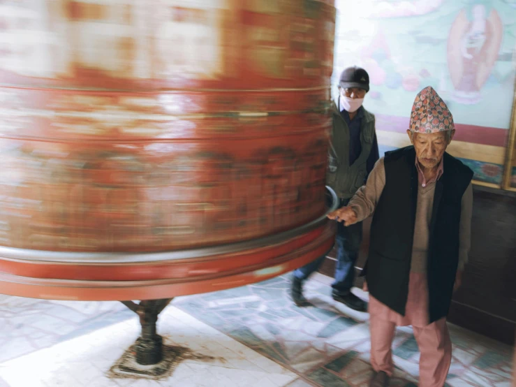 an older woman stands next to some large pipes