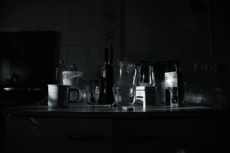 s of a kitchen counter with coffee cups, blender, and water in the dark