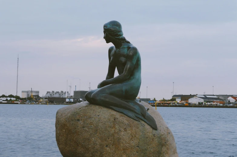 a statue of a woman sitting on a rock