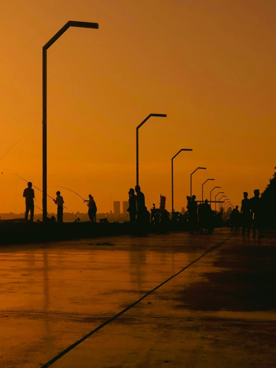 people walking and waiting at an intersection at sunset