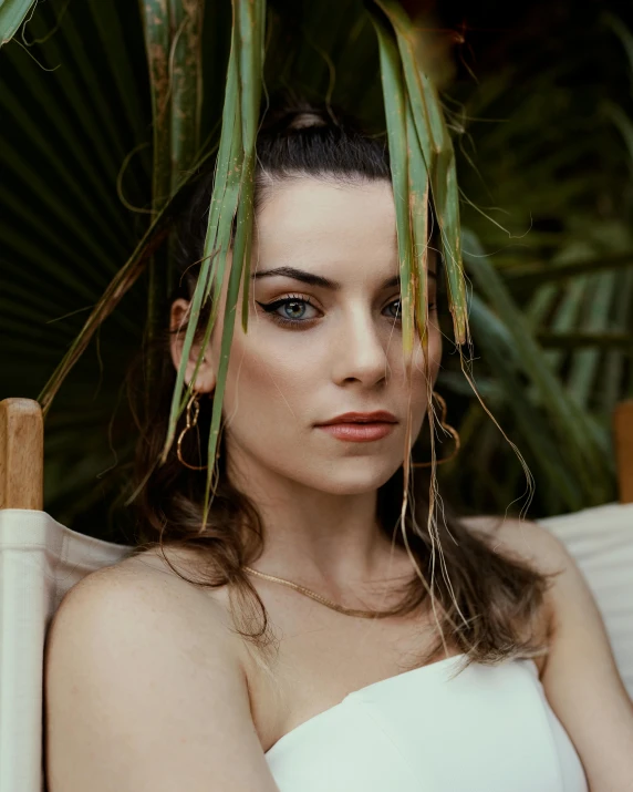 a beautiful young woman sitting on a chair in the shade