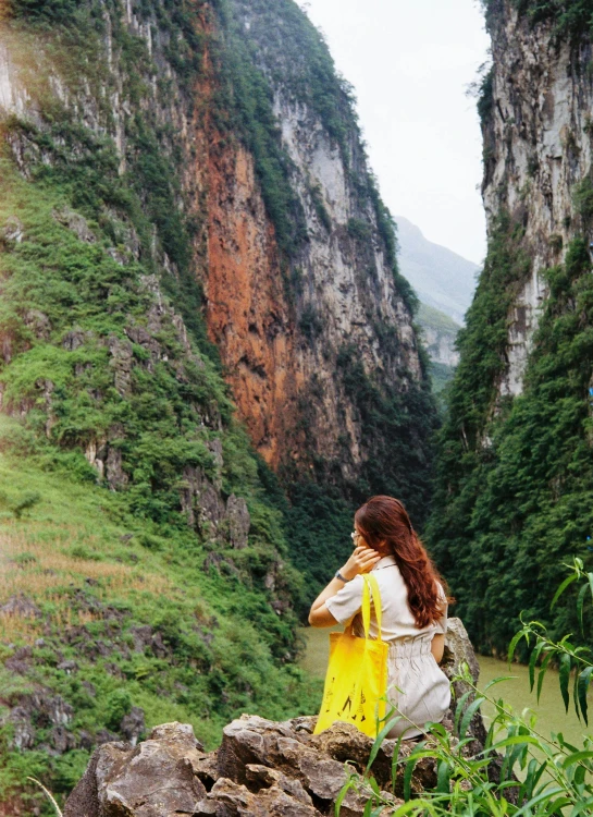 woman sitting on rock with view of mountains and river