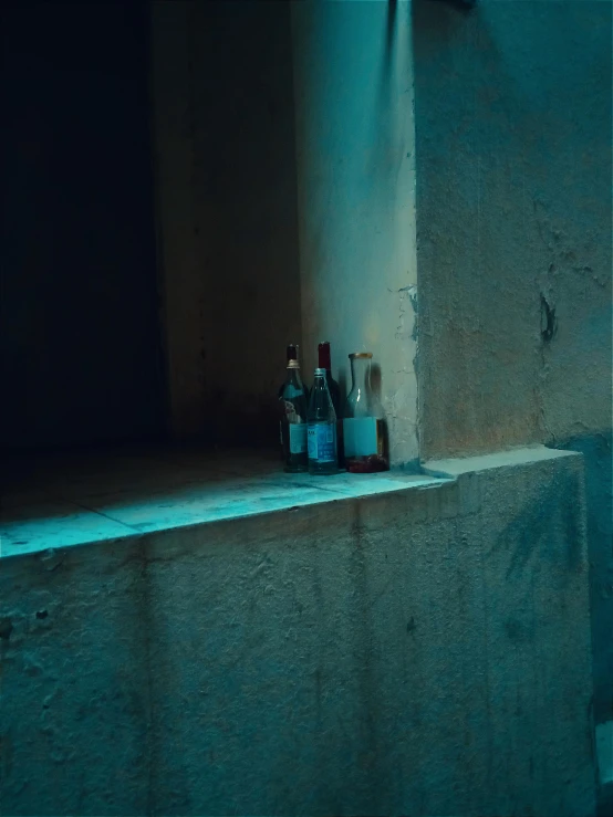 several bottles of alcohol are sitting in front of an illuminated wall