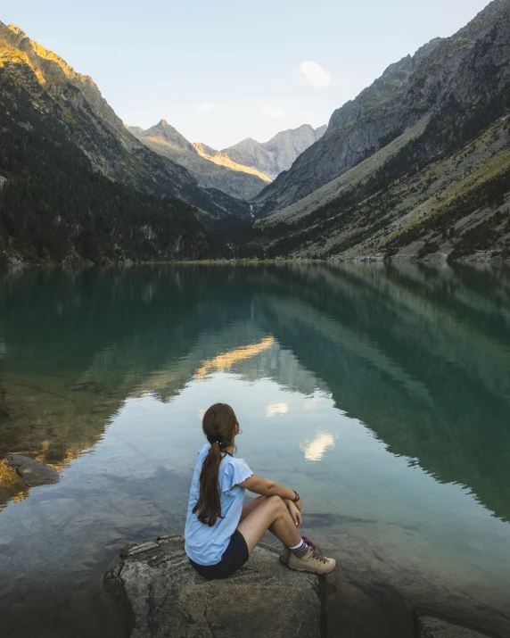 a woman sits on rocks overlooking a large lake