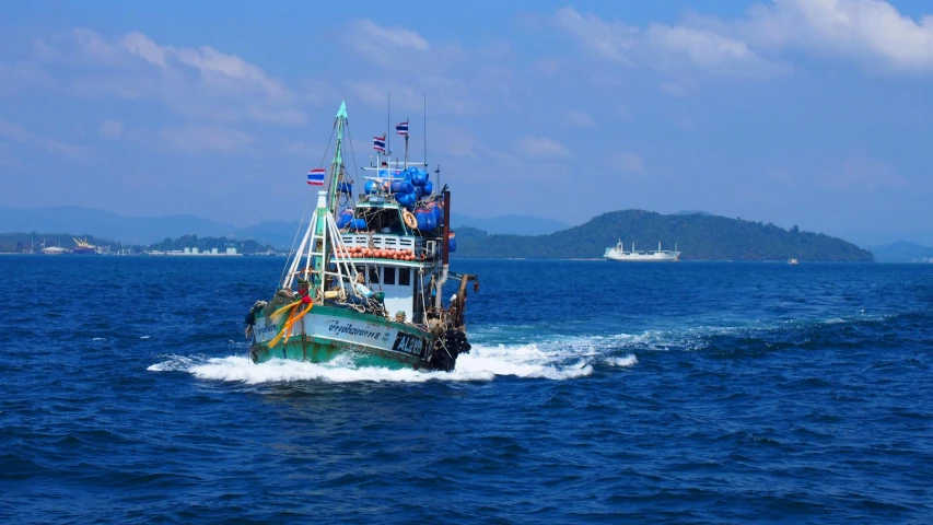 large boat in open ocean with mountains in background