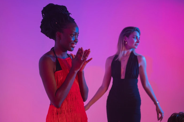 two women in evening wear in a pink and purple lit room