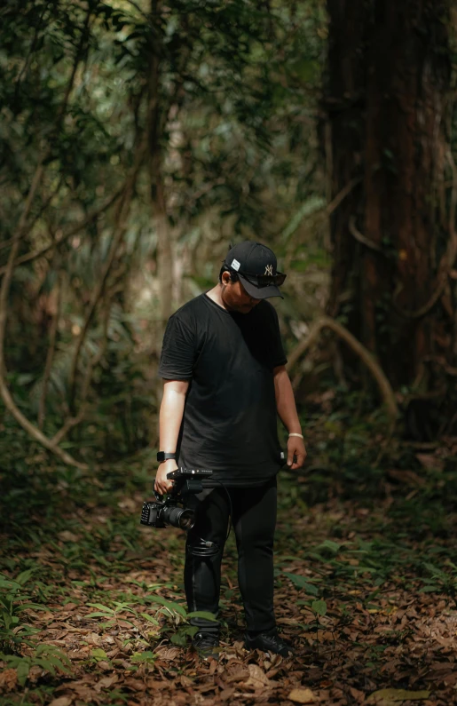 a man in black standing on a forest path