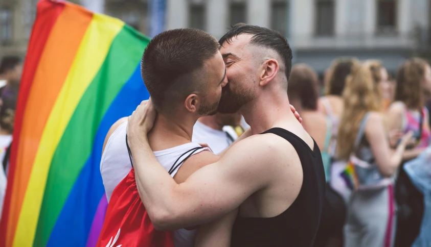 two men hugging in front of rainbow flags