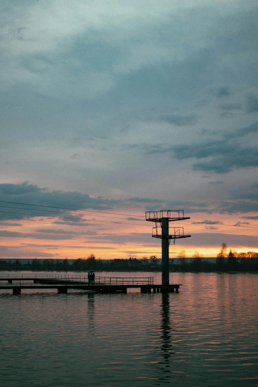 sunset over calm water with several dock posts sticking out of the water