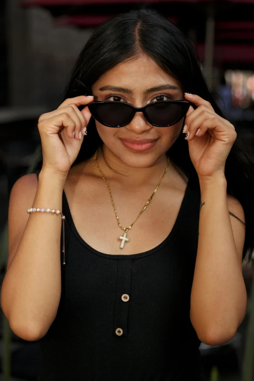woman wearing sun glasses with small cross on her necklace