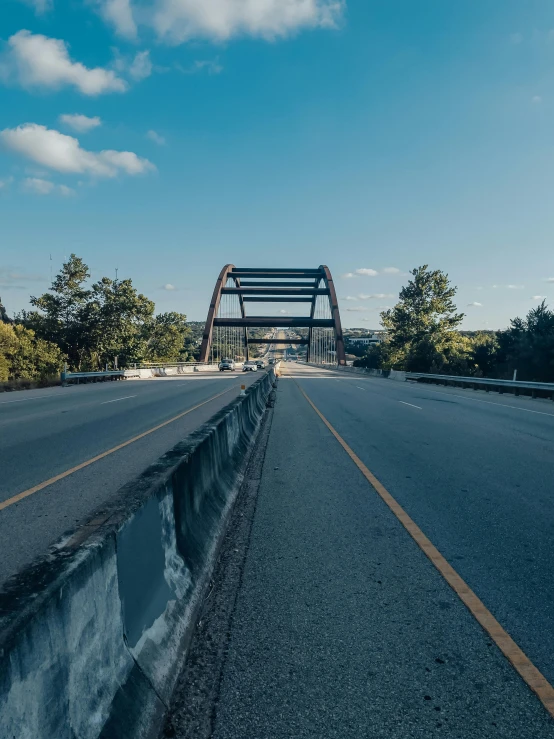 a bridge spanning an open country highway with a fallen over ledge