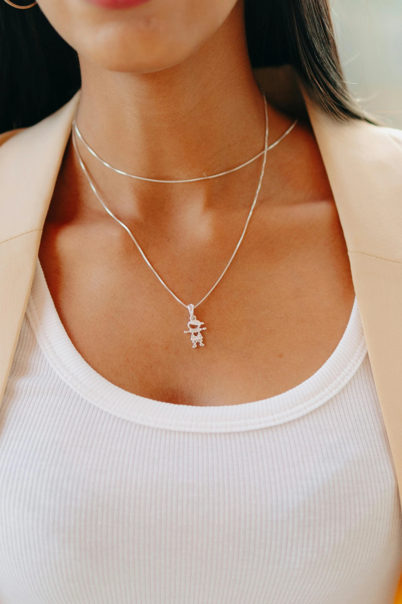 a woman with a white top wearing a small necklace