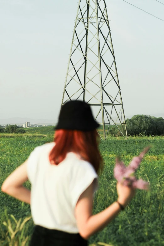 woman standing on field with flowers near electric pole