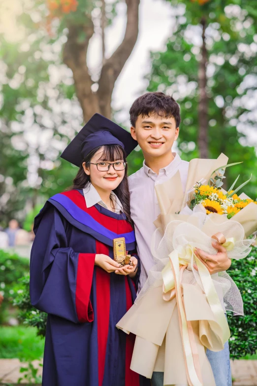 a girl holds her diploma and her boyfriend gives him her flowers