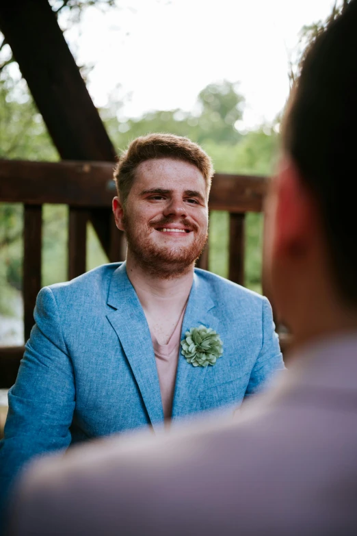 there is a man wearing a suit jacket and flower brooch