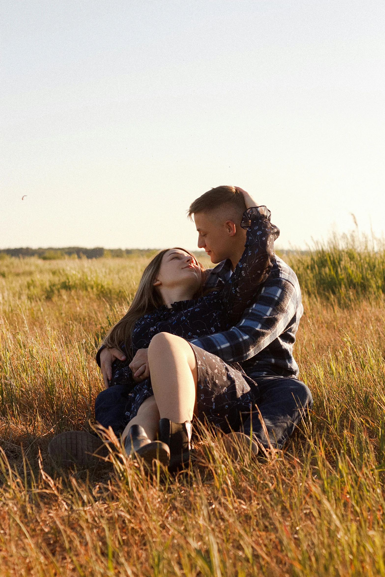 a couple sit on a bench and hug in the grass