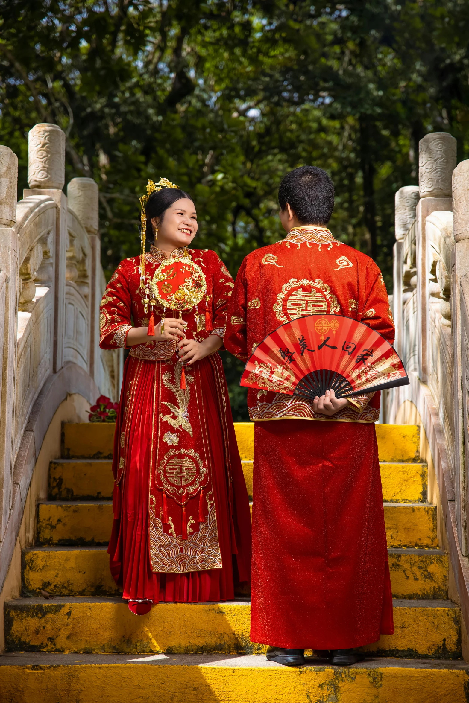 two asian brides stand on some steps dressed in traditional clothing