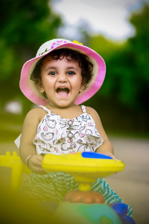 a toddler girl wearing a pink hat holds a toy