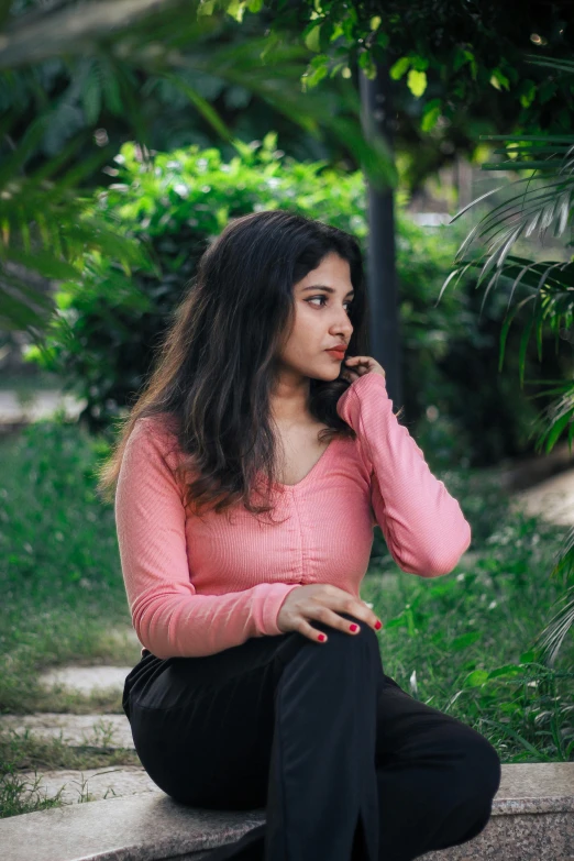 a woman sitting in the grass on her cell phone