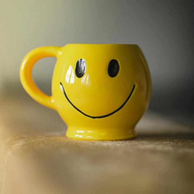 the coffee mug is yellow with a smiley face on it