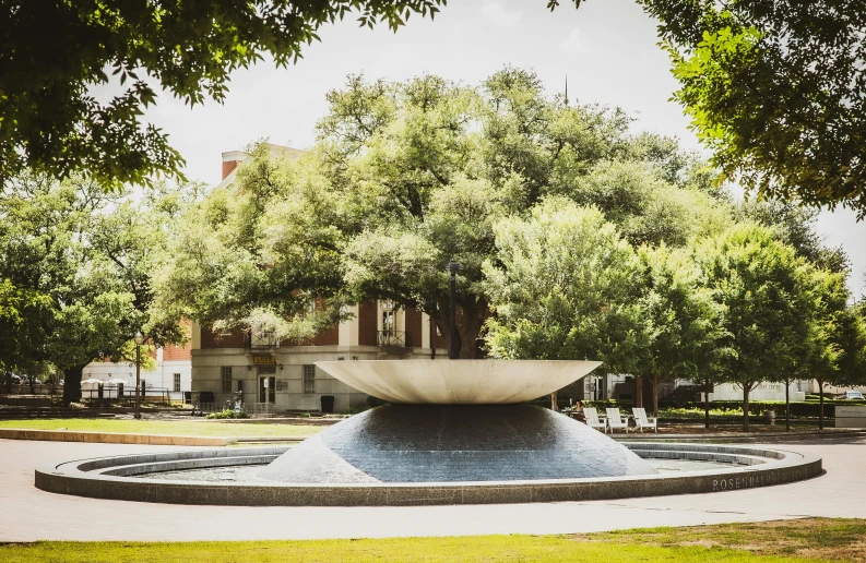 a large fountain is surrounded by trees and benches