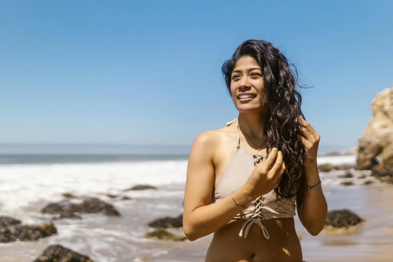 the young woman is standing by the ocean, and posing