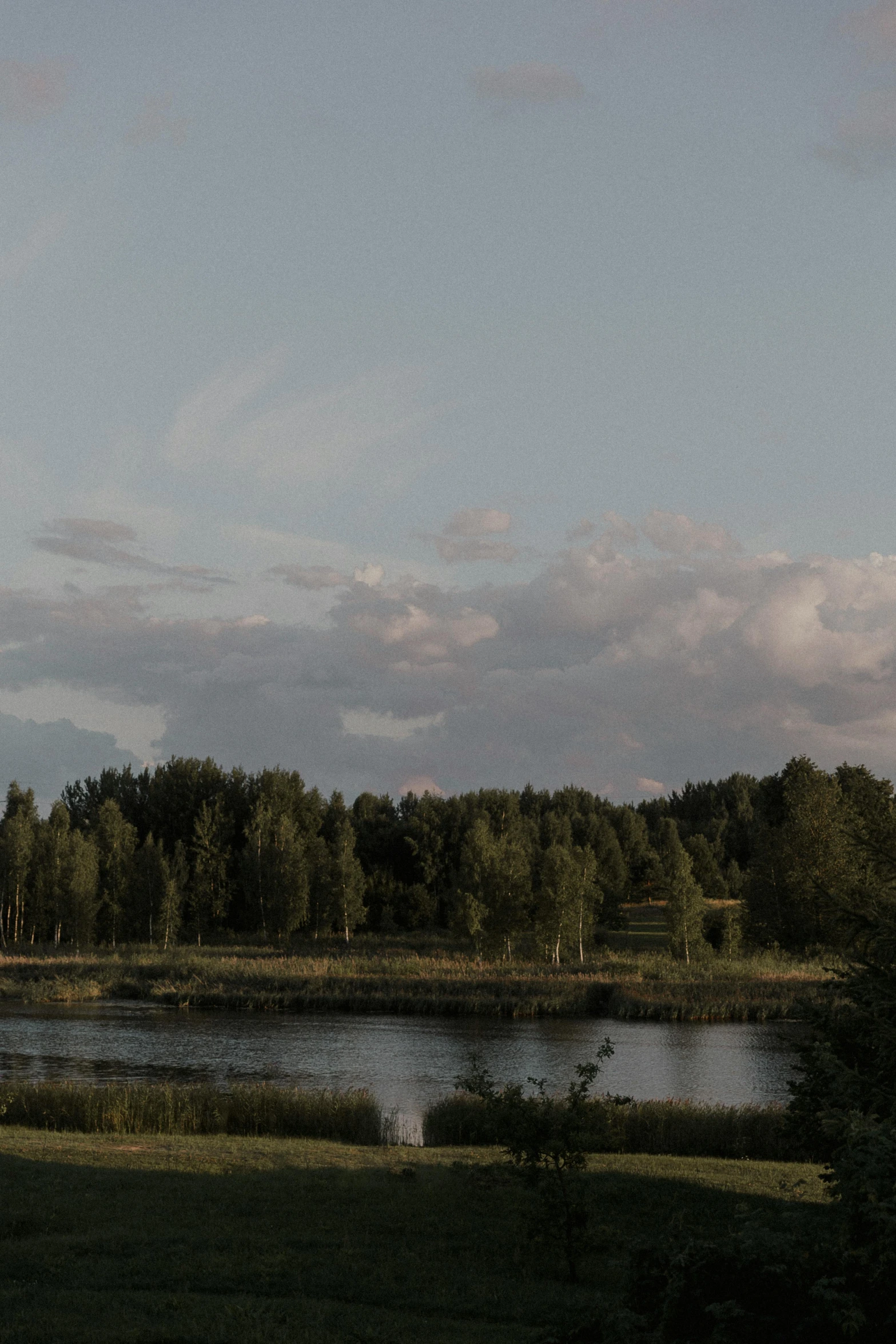 a lone parasail glides through the clouds as it passes by the lake