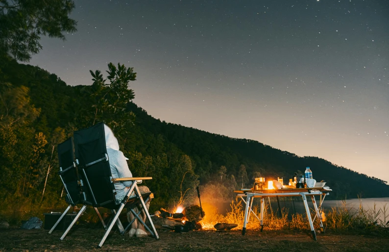 an evening camping scene with camping gear in the foreground