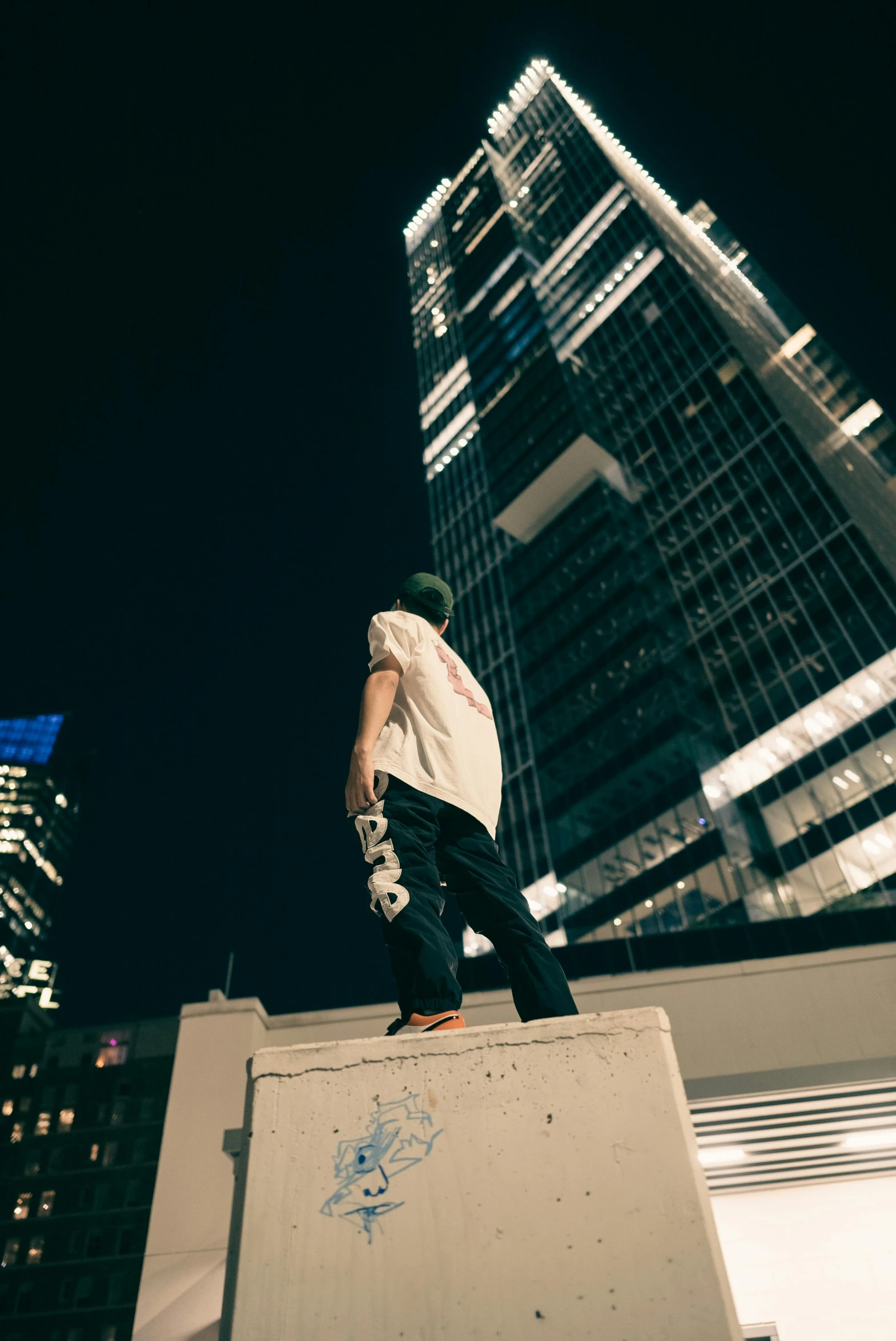 the boy stands on top of a ramp that is overlooking a skyscr at night