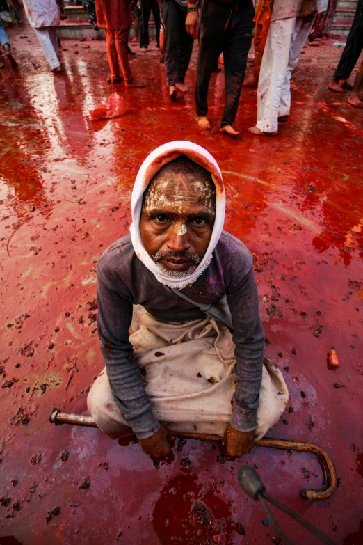 a man sitting on the ground in the middle of red paint